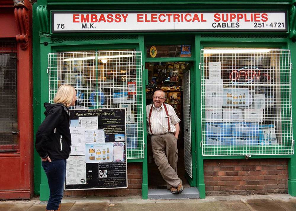 Man standing outside a green electrical shop